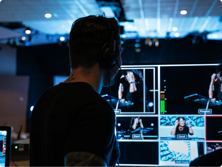 Live broadcast control room with a producer watching multi-camera monitors